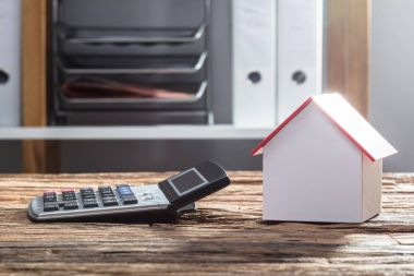 Yakın çekim ev modeli ve ahşap masa hesap makinesi
