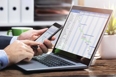 Gantt şeması ile cep telefonu üzerinde çalışan bir işadamının'ın el Close-Up