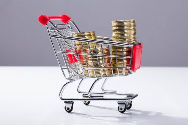 Alışveriş sepeti ile yığılmış altın sikke dolu, yakın çekim
