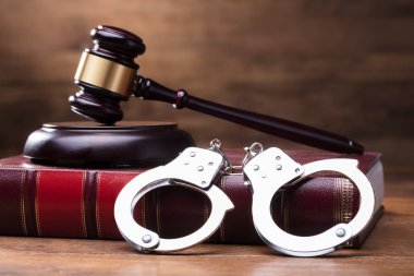 Gavel And Handcuffs On The Law Book Over The Wooden Table Background clipart