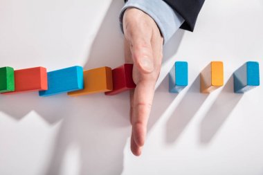 Masanın üzerine düşmesini renkli Domino durdurma bir işadamının yüksek açılı görünüş