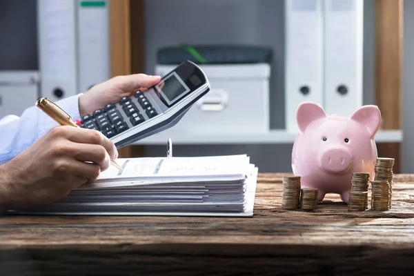 Mão Empresário Calculando Bill Com Moedas Empilhadas Piggy Bank Mesa — Fotografia de Stock