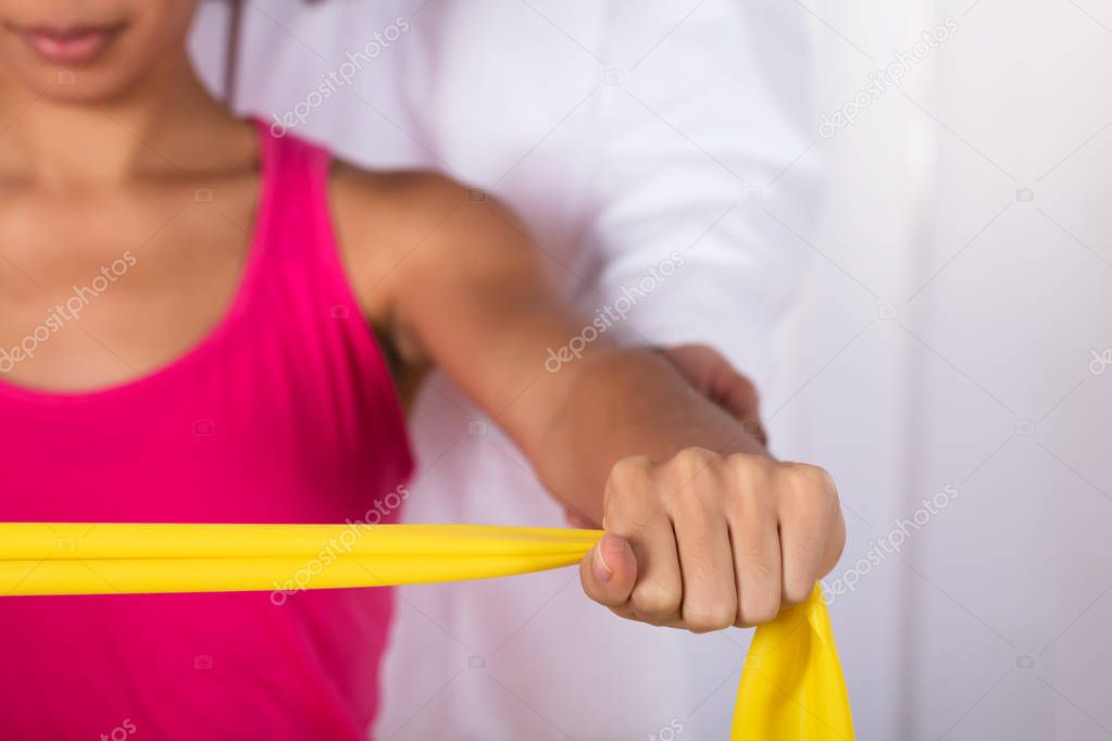 Physiotherapist Assisting Woman While Exercising With Exercise Band