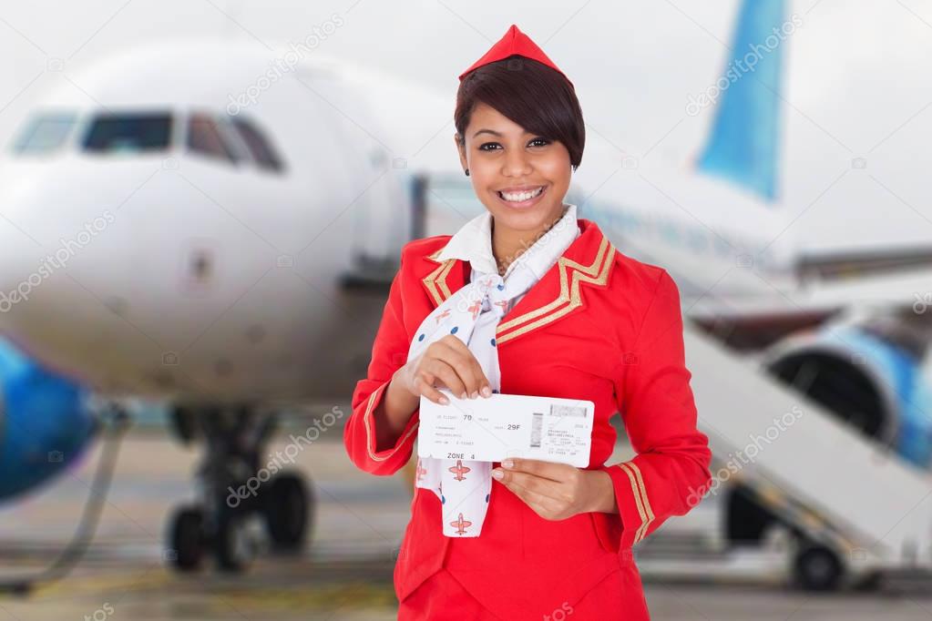 Portrait Of A Smiling Young Stewardess In Front Of Airplane