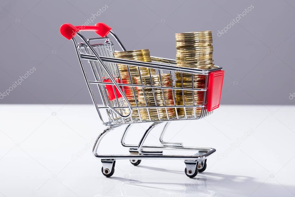 Close-up Of Shopping Cart Filled With Stacked Golden Coins