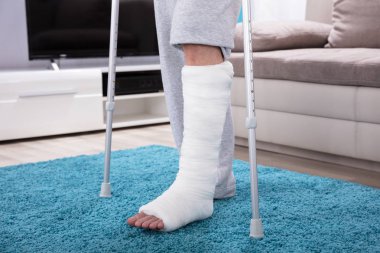 Man With Broken Leg Using Crutches For Walking On Blue Carpet clipart