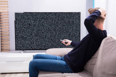 Televizyon sinyal bakarak kanepede oturan adam