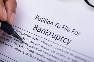 Close-up Of A Person's Hand Filling Bankruptcy Form clipart