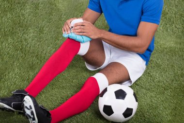 Diz üstü buz paketi uygulamadan bir yaralı erkek futbol oyuncusu Close-Up