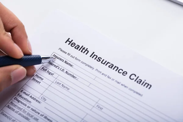 Close Van Een Menselijke Hand Invullen Health Insurance Claimformulier Met — Stockfoto