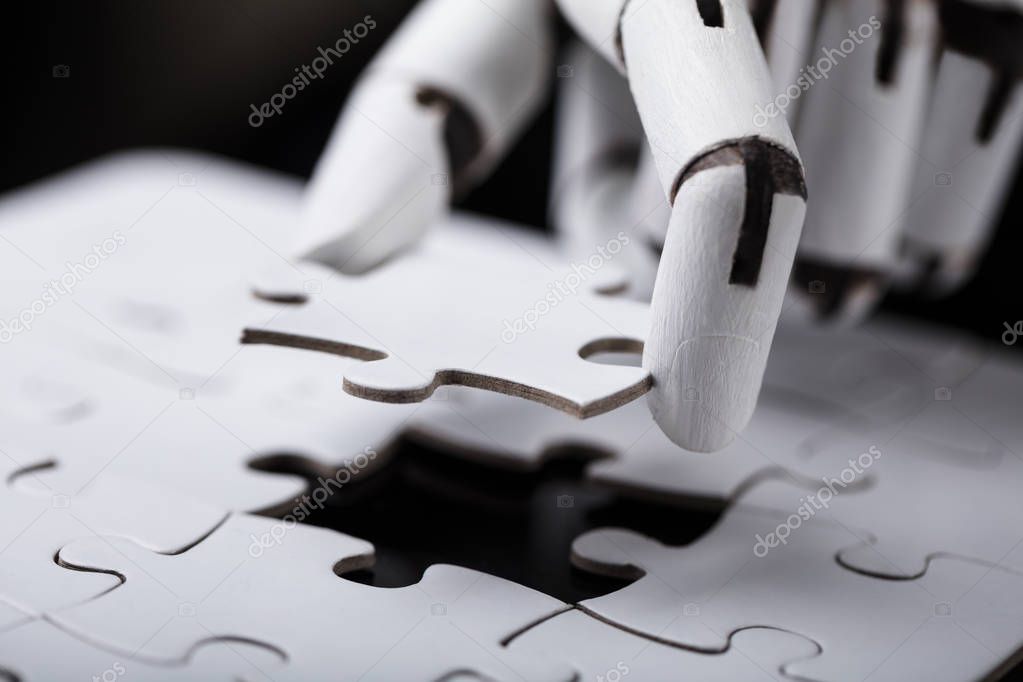 Close-up Of A Robot's Hand Holding Jigsaw Puzzle
