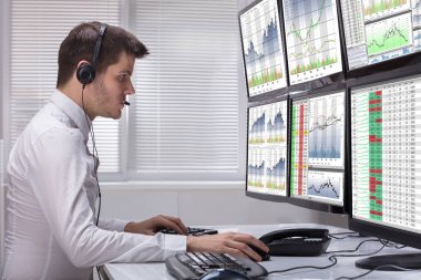 Grafikler birden çok bilgisayar ekranlarında analiz bir genç erkek borsa Broker yan görünüm
