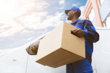Düşük açılı görünümü yükleyicisi adam Van Holding karton kutu ayakta