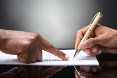 Belge üzerinde altın kalem ile imzalama bir kişi önünde parmakla