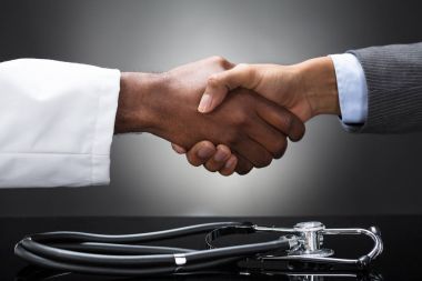 Doktor ve iş adamı el sallayarak önünde Resepsiyon stetoskop