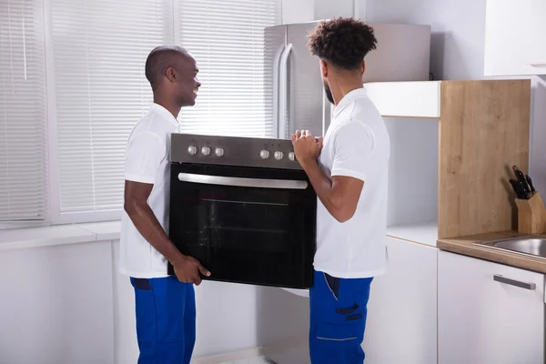 Deux Travailleurs Masculins Uniforme Fixant Four Dans Cuisine Maison — Photo