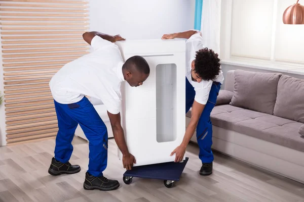 Two Young Male Movers Placing White Cabinet Wheel Living Room — Stock Photo, Image