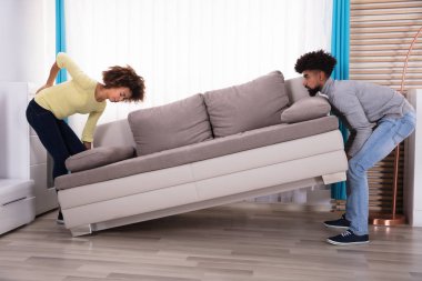 Oturma odasında kanepede kocası ile kaldırma sırasında Backpain olan kadın