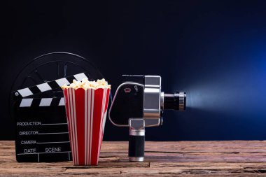 Patlamış mısır ve Clapper tahta karşı mavi arka plan ile bir ışıklı film kamera