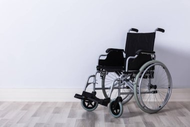 Duvarın önünde siyah renkli boş tekerlekli sandalye