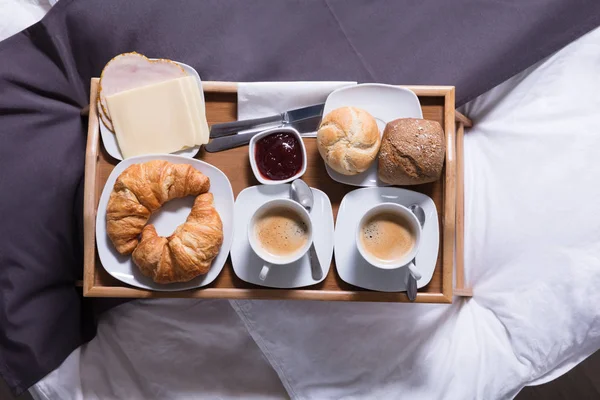 焼きたてのクロワッサンと朝食ベッドの上のお茶のカップ — ストック写真