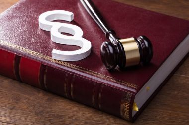 Büyük beyaz paragraf sembolü, çekiç ve hukuk kitabını ahşap masa üzerinde yakın çekim