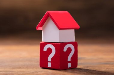 Minyatür kırmızı ev Model ahşap masanın üzerinde soru işaretleri ile kırmızı blok