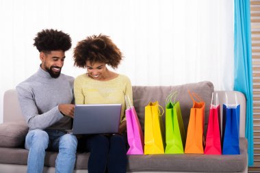 Genç çift çok renkli alışveriş torbaları Divan ile laptop alışveriş Online
