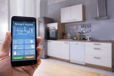 Mobilephone mutfakta üzerindeki akıllı ev sistemi kullanan bir kişinin el Close-Up