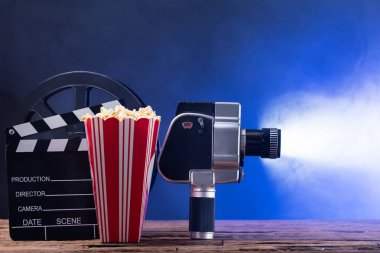 Patlamış mısır ve Clapper tahta karşı mavi arka plan ile bir ışıklı film kamera