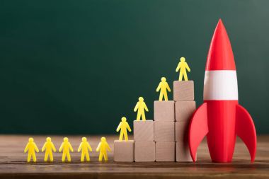 Yakın çekim roket yanı sıra sınıfta ahşap bloklar üzerine sarı insan figürleri