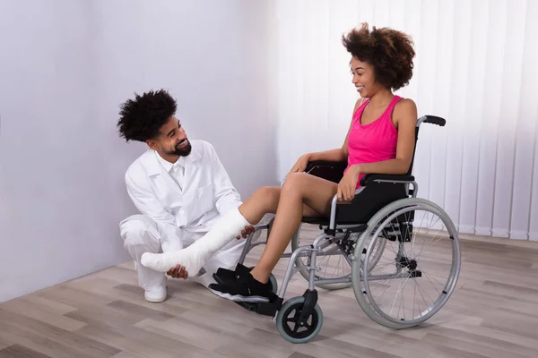 Erkek Fizyoterapist Kadın Hasta Tekerlekli Sandalye Üzerinde Oturan Bacak Incelenmesi — Stok fotoğraf
