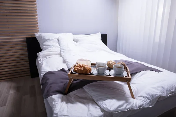 焼きたてのクロワッサンと朝食ベッドの上のお茶のカップ — ストック写真