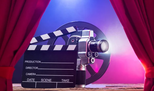 Clapperboard 和胶片卷轴的照明电影相机对彩色背景 — 图库照片