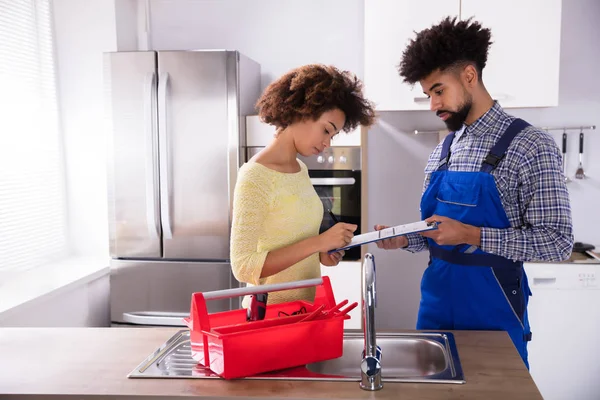 Jovem Encanador Masculino Olhando Mulher Assinando Fatura Cozinha — Fotografia de Stock