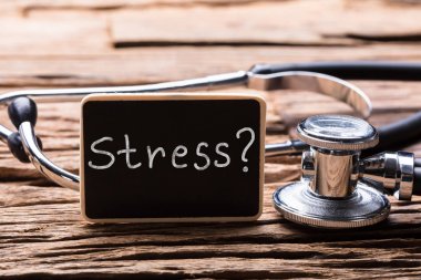 Close-Up stetoskop ile stres Word ahşap arka plan üzerinde gösterilen kayrak