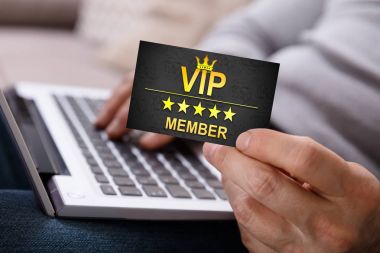 VIP üye kartı tutan dizüstü bilgisayar kullanarak bir kişinin ele Close-Up