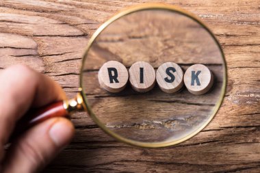 Bir kişinin el ahşap masanın üzerinde Risk blok Büyüteç aracılığıyla bakarak Close-Up