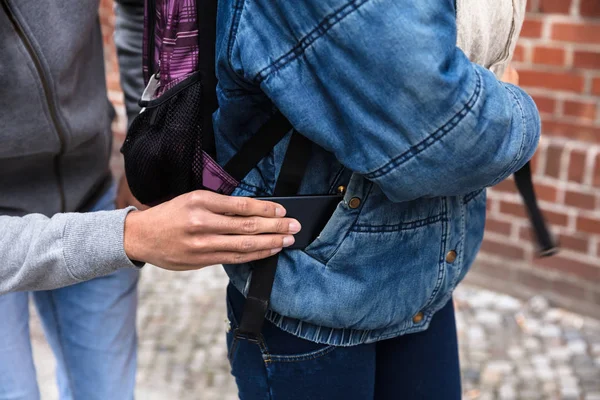 Close-up Of A Thief\'s Hand Stealing Purse From Backpack