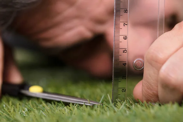 用剪刀割草时使用测量秤的人特写 — 图库照片