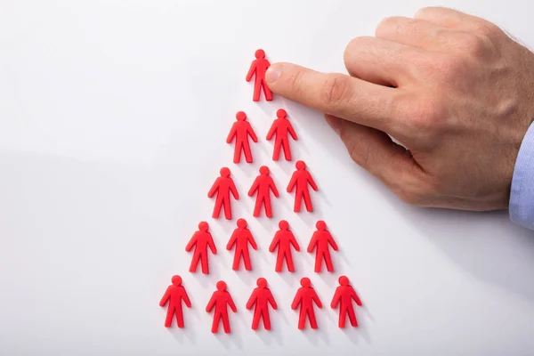 Close Mão Uma Pessoa Organizando Figuras Humanas Vermelhas Forma Triangular — Fotografia de Stock
