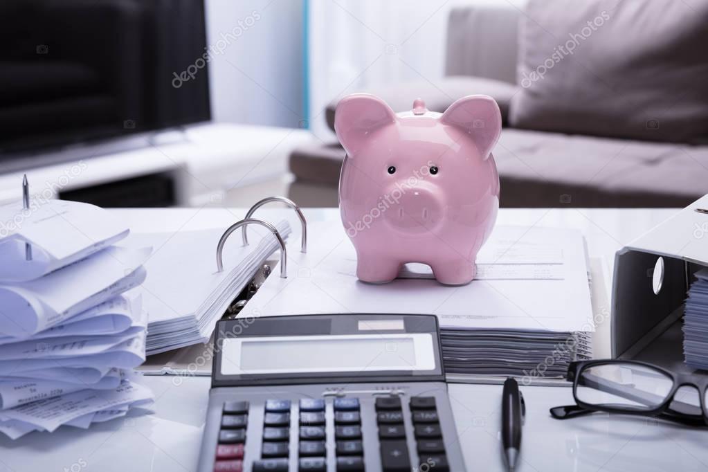 Close-up Of Piggybank And Document With Receipts And Calculator On White Desk