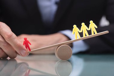 Kırmızı figür ve üç sarı rakamlar arasındaki dengesizlik tahterevalli üzerinde gösterilen işadamı'nın el