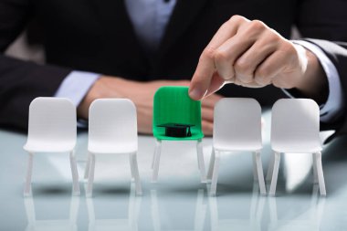 Yakın çekim yeşil sandalye mezuniyet şapka ile seçtiğiniz bir işadamının'ın el