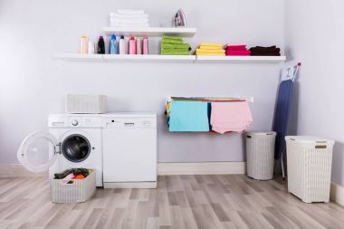 Basket Full Of Dirty Clothes In Front Of Washing Machine At Laundry Room clipart