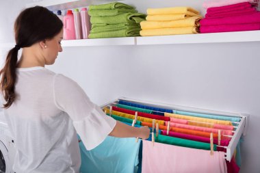 Çamaşır odasında ıslak giysiler asan genç bir kadının yan görüntüsü