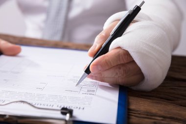 Bir işadamının kırık kol ahşap masa sağlık sigortası talep formu doldurma ile yakın çekim