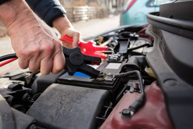 Otomobilin ölü pil şarj etmek için bağlantı kablosu kullanarak bir kişinin ele Close-Up