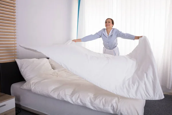 Smiling Young Female Housekeeper Housekeeper Arranging Bedsheet Bed Hotel Room — Stok Foto