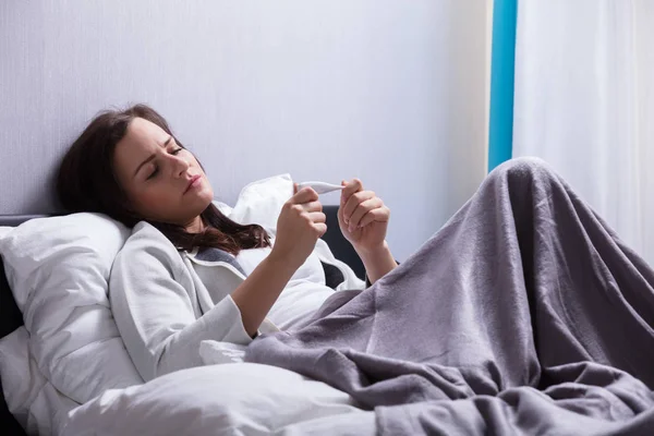 Zieke Jonge Vrouw Liggend Bed Controleren Lichaamstemperatuur Met Thermometer — Stockfoto